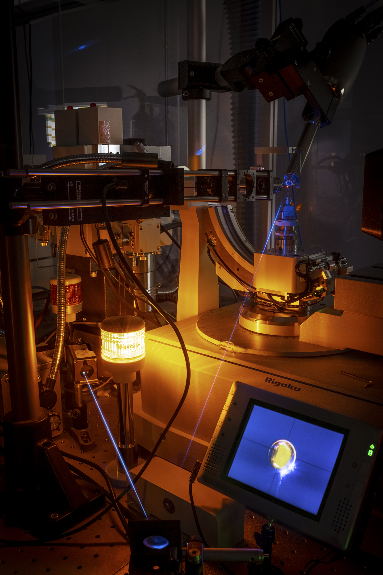 A crystal of a red fluorescent protein placed in a combined instrument consisting of a fluorescence microscope and an X-ray diffractometer. The crystal glows red when illuminated by a blue laser beam. (Photo: Petr Pachl / IOCB Prague)